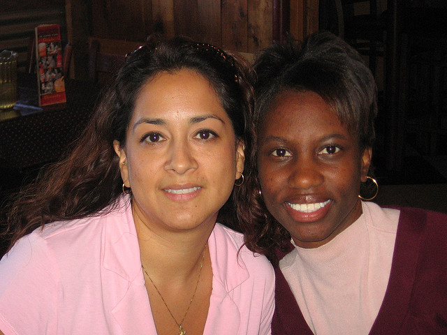 Two women, one with light brown skin, the other with dark brown, posing for a picture.