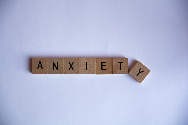The word "anxiety" spelled with wooden Scrabble letter tiles.