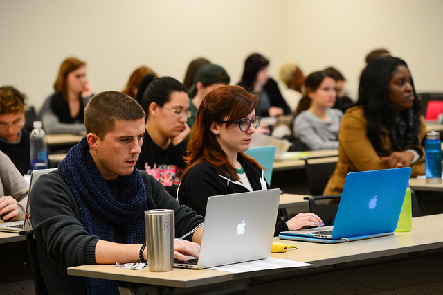 College students in a classroom with laptops.