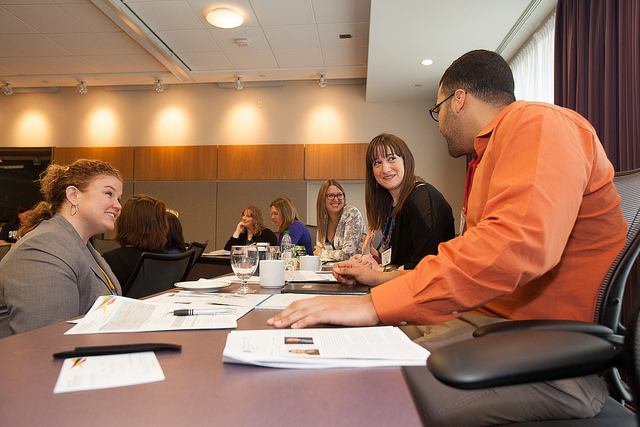 Coworkers at a long table listening to a fellow coworker.