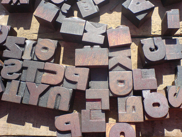 Wood letter blocks spread on a table in disarry.