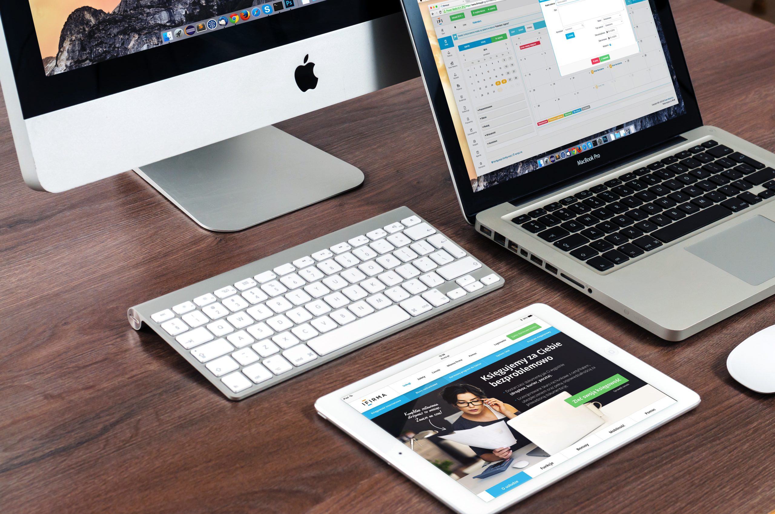 A computer, keyboard, laptop and tablet on a desk.