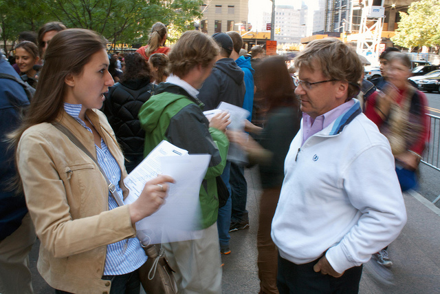 A woman and man talking to each other on a busy street.