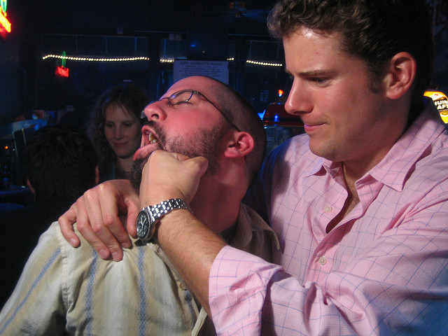 One man punching another man in a crowded public place.