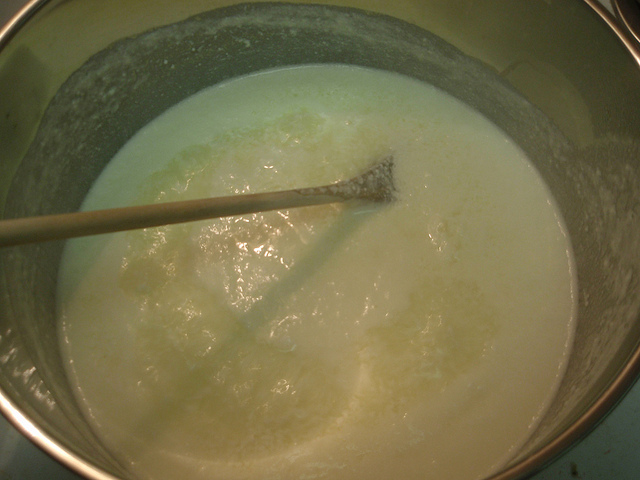 A bowl with hot milk and wooden spoon.