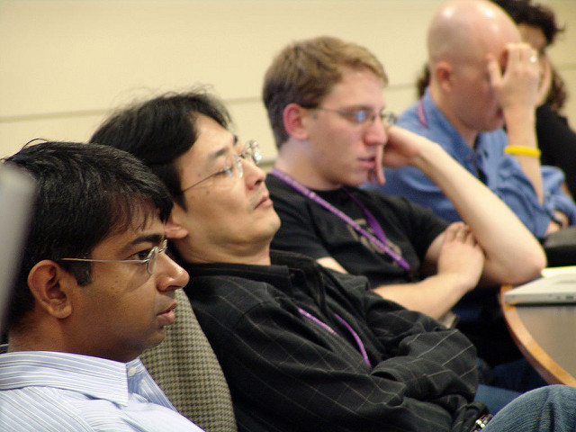 Four seated men looking bored or asleep.
