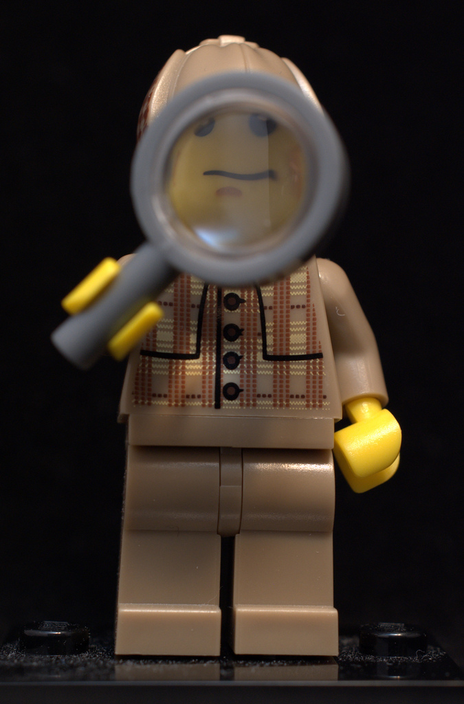 A lego person looking through a magnifying glass.