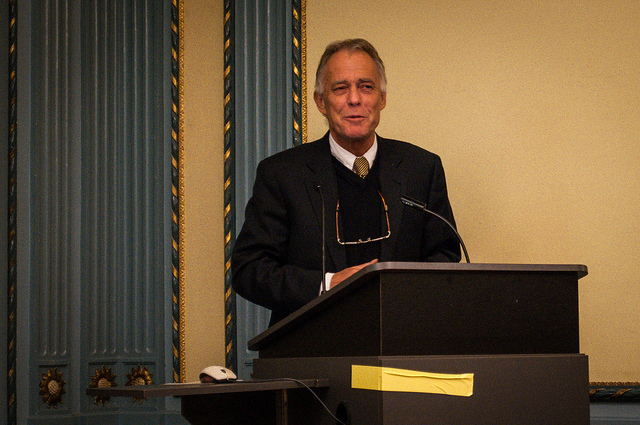 A man in a suit and tie speaking behind a podium.