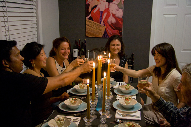 Six people at a dinner table toasting.