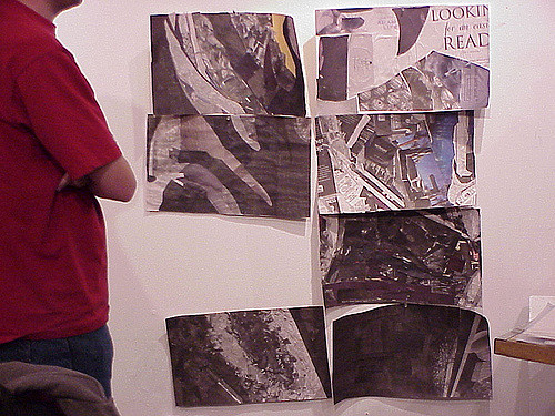 Person in red shirt looking at seven abstract images displayed on a wall.