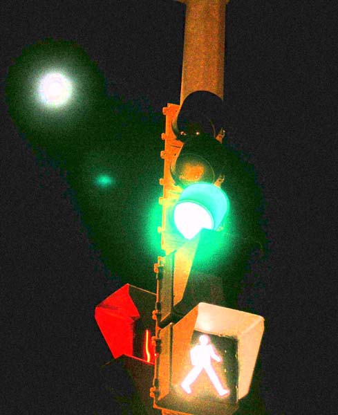 A green stop light with a lighted sign of a person walking.