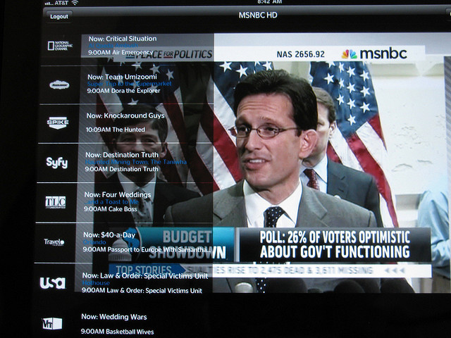 MSNBC news on a television screen with logos to the side including "National Geographic Channel, Spike, Syfy, TLC, Travel Channel, and USA."