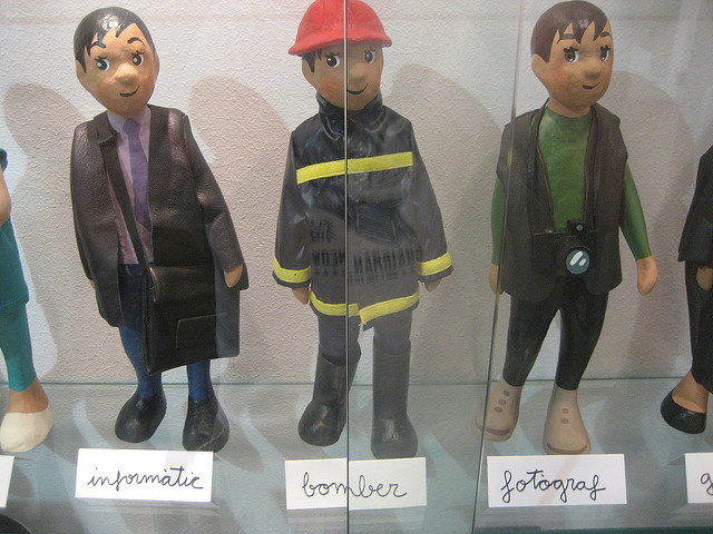 Three male figurines dressed in business clothes, a fireman's uniform, and as a photographer wearing a camera.