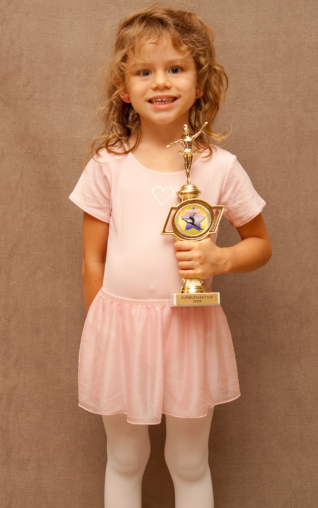 A young girl holding a trophy and smiling.
