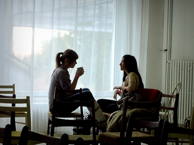 Two young women facing each other and having a discussion.