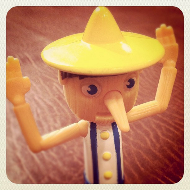 A Pinnochio figurine with long nose and a yellow hat.