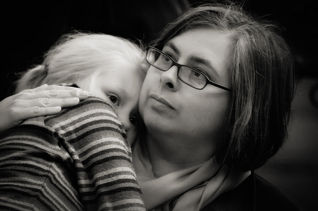 A woman holding and patting and comforting a child.