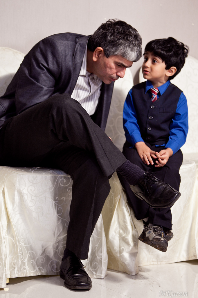 A father and son sitting down with the father tipping his head to listen to the son.