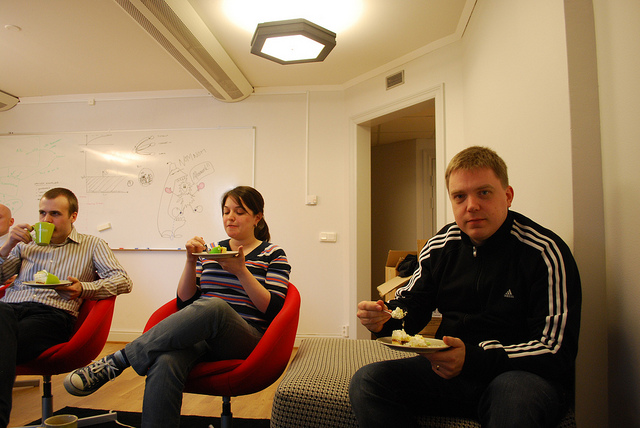 Co-workers sitting in a classroom together eating cake.