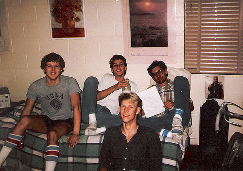 Four college students hanging out in a dorm room.