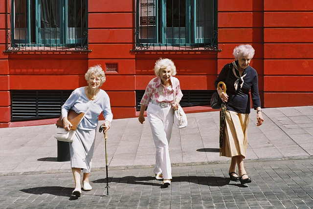 Three elderly female friends smiling and crossing the street.